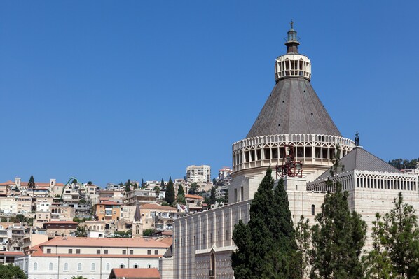 A historic building with a prominent dome and a bell tower, surrounded by densely packed residential buildings. - Legacy Nazarethe Hotel (Nazareth)
