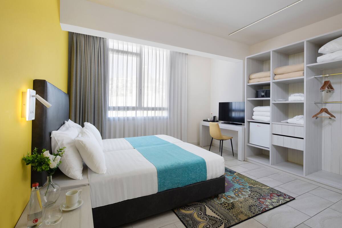 Ein Hotelzimmer mit Bett, Schreibtisch, Fernseher und Kleiderschrank.