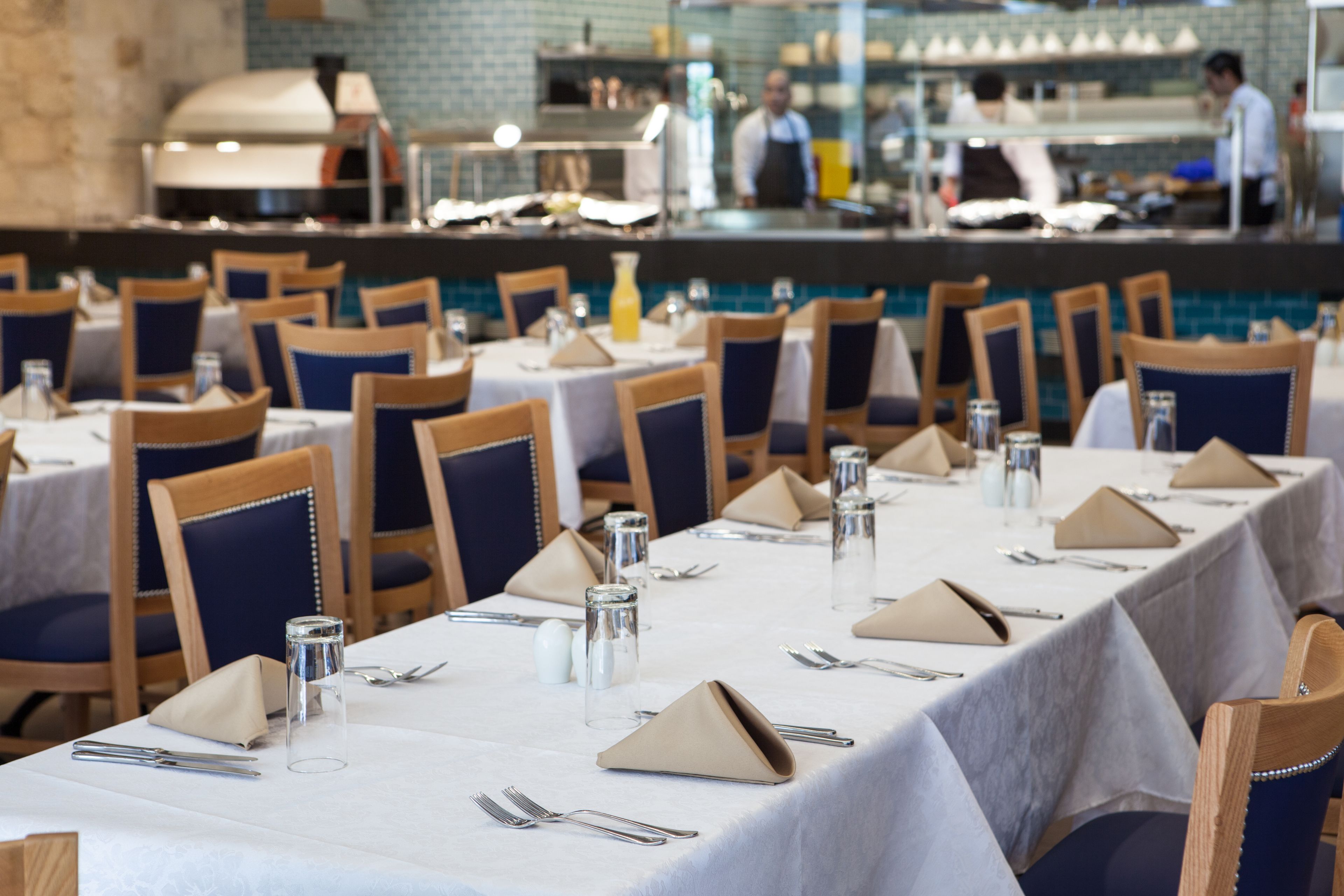 A restaurant with multiple tables set for dining, each with chairs, cutlery, and glassware.