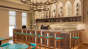 A bar area with a long counter, multiple bar stools, and a decorative ceiling light fixture. - Legacy Nazarethe Hotel (Nazareth)