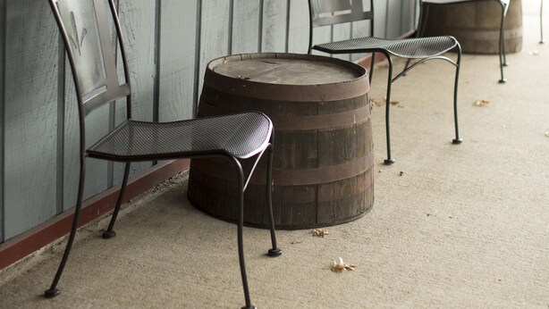 A row of metal chairs and a wooden barrel on a concrete floor against a wooden wall. - Rhinebeck Village Inn (Rhinebeck)
