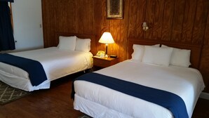 A hotel room with two beds, wooden paneling, a nightstand with a lamp, and a framed picture on the wall. - Rhinebeck Village Inn (Rhinebeck)