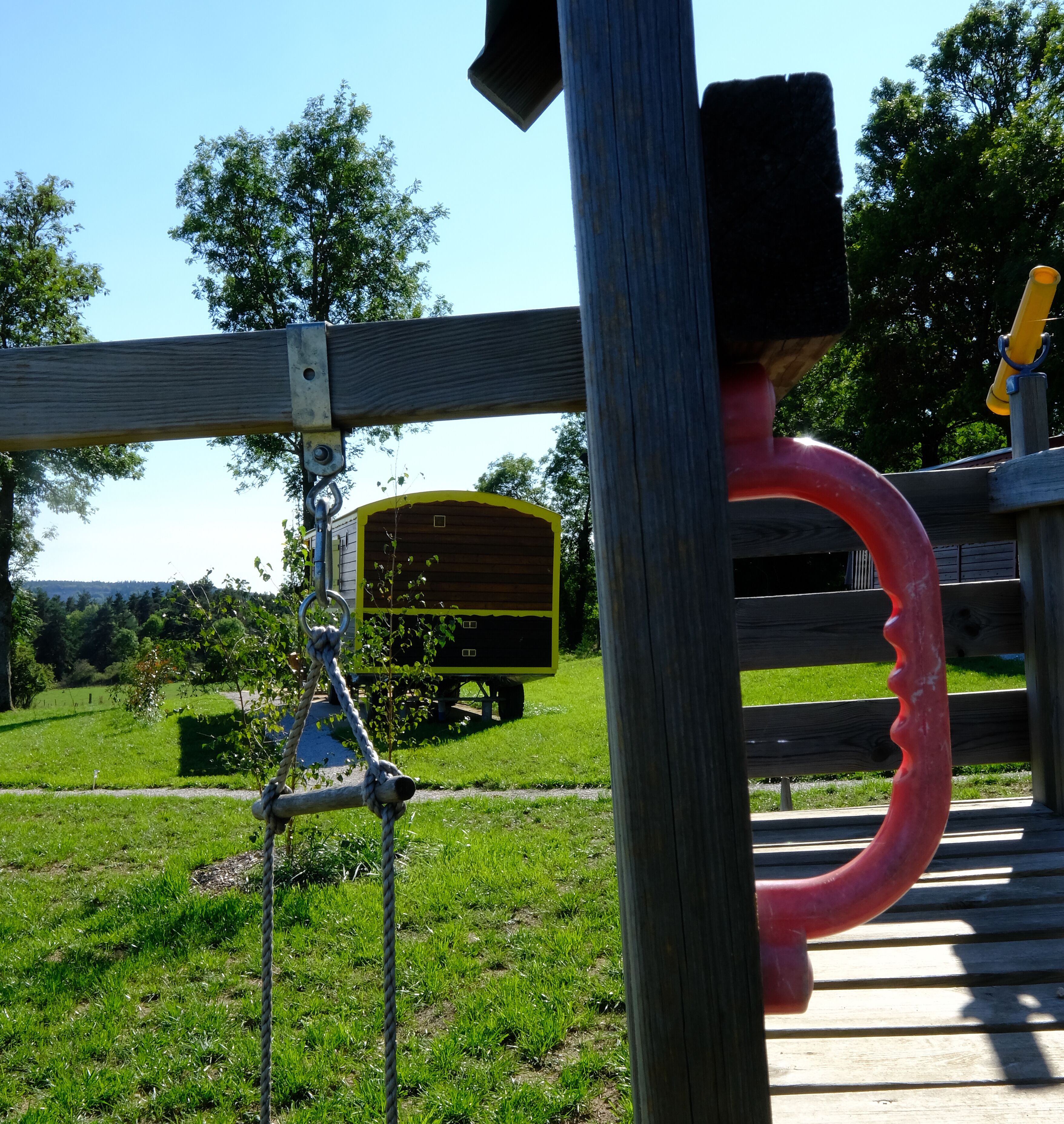 A playground with a wooden swing set and a slide.
