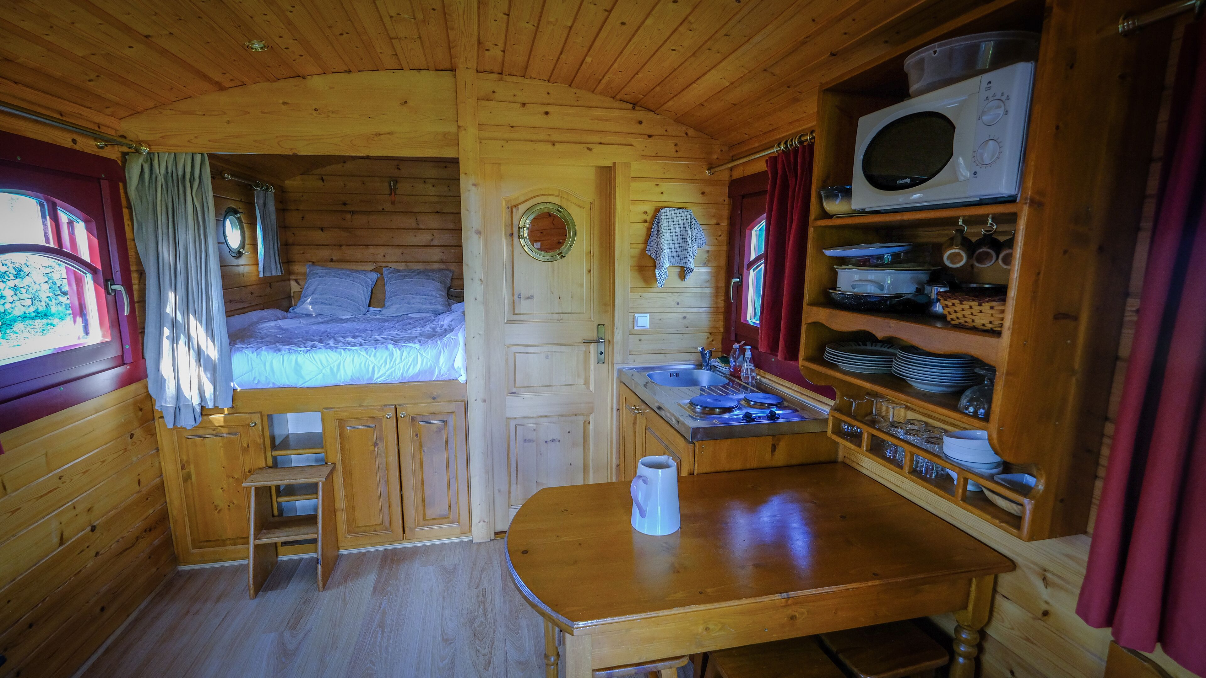 L’intérieur d’un chalet accueillant, avec un lit, un coin cuisine et une table à manger.
