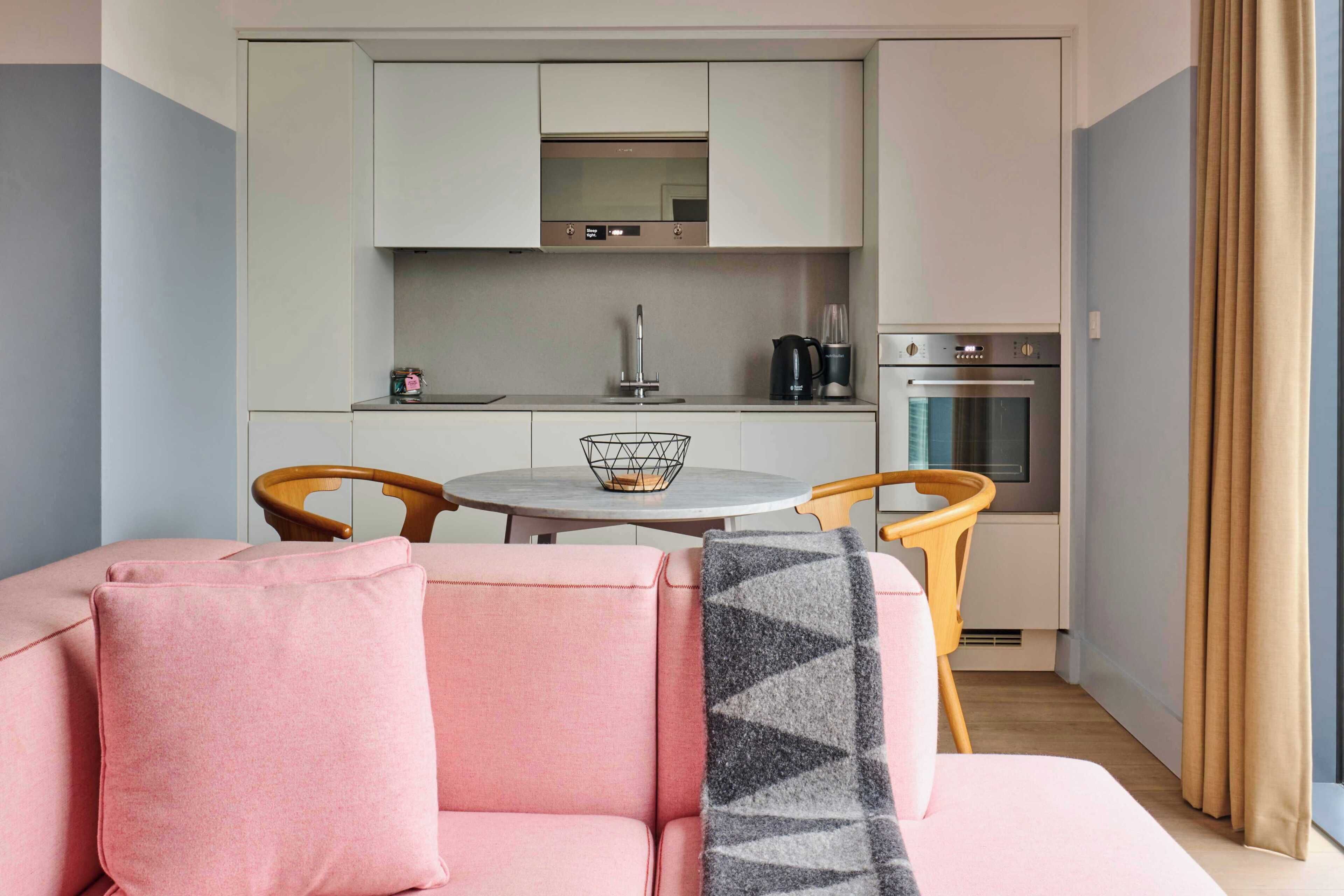 Un espacio habitable compacto con kitchenette, una mesa de comedor y un sofá.