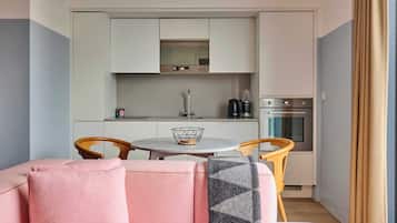 Un espacio habitable compacto con kitchenette, una mesa de comedor y un sofá.