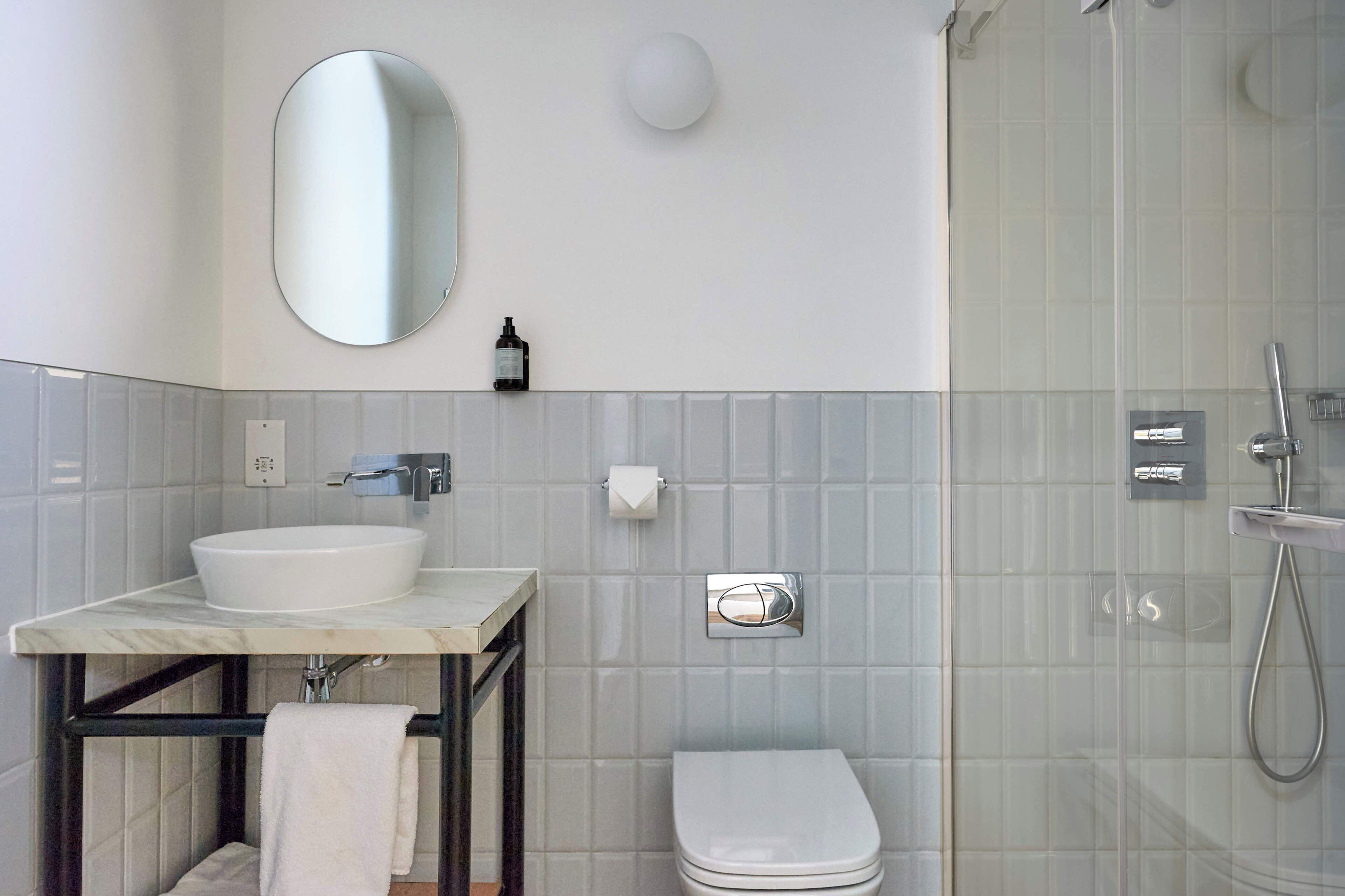 A bathroom with a sink, toilet, mirror, and shower.