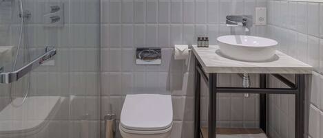 A modern bathroom with a glass shower enclosure, a white toilet, and a marble sink with a mirror above.