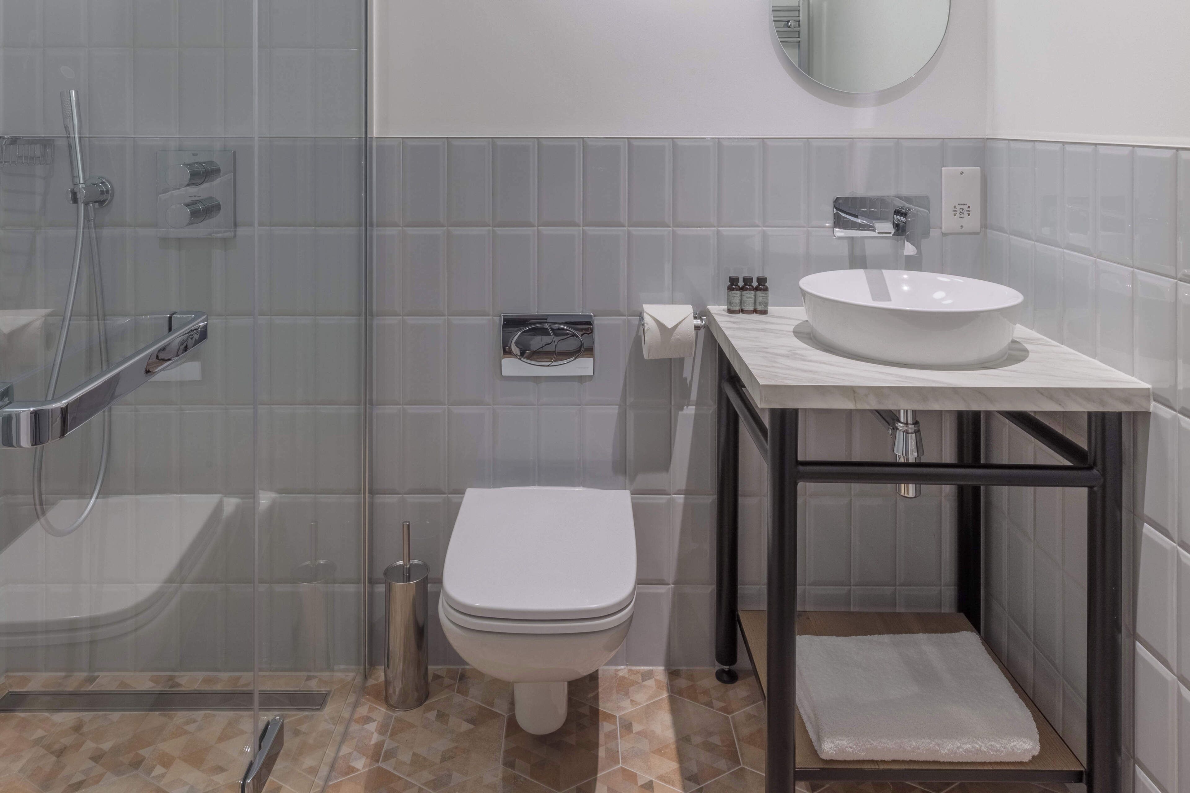 A modern bathroom with a glass-enclosed shower, a white toilet, a marble sink, and a small towel rack.