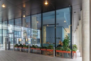 A modern building with large glass windows, indoor plants, and a reception area. - Leman Locke (London)