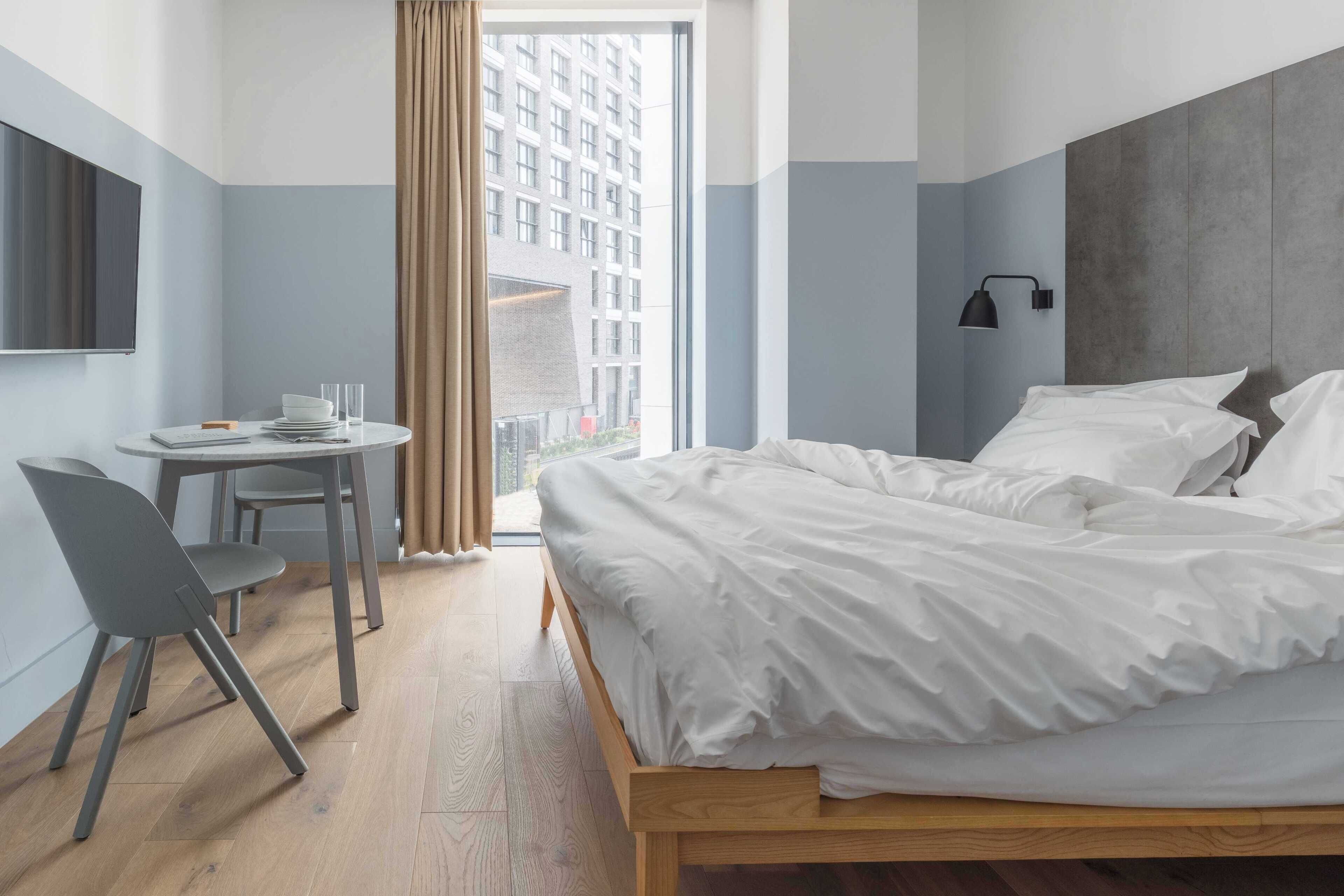 Ein modernes Hotelzimmer mit Bett, Schreibtisch und Stuhl.