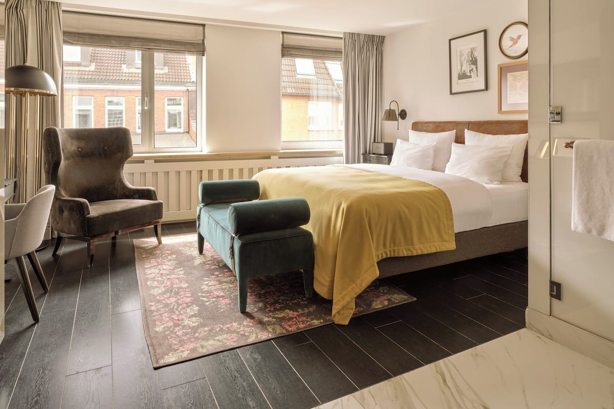 Une chambre d’hôtel avec un lit, une chaise, un bureau et une vue sur l’extérieur.