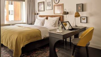 Una habitación de hotel con cama, escritorio, silla y ventana con cortinas.