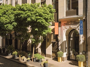 Egy épület, melynek előterében egy nagy fa áll, egy tábla jelzi a „The Nikolai Hotel” nevét, és egy lámpaoszlop is található ott.