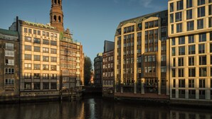 Un canal bordé de bâtiments des deux côtés, notamment une tour d’église et des constructions modernes.