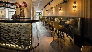 Un espace bar moderne doté d’un comptoir incurvé, de tabourets de bar et d’un coin salon avec un canapé et des fauteuils.