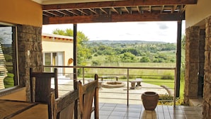 A spacious balcony with a stone wall, a rustic wooden chair, and a large potted plant. - Country Park (Muldersdrift)