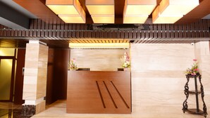 A reception desk with a wooden finish, a marble floor, and a wall-mounted air conditioning unit above. - Visitel - A Boutique Hotel (Kolkata)