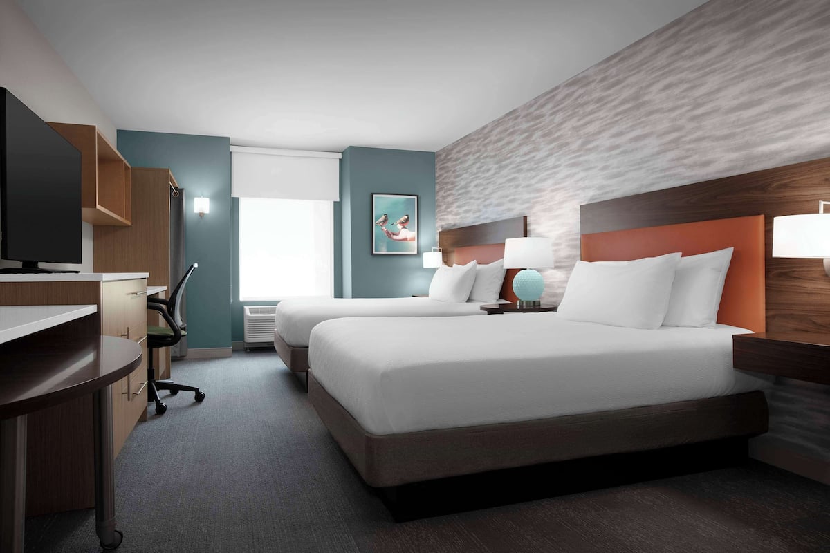 Une chambre d’hôtel avec deux lits, un bureau et une télévision.