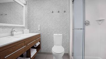 A modern bathroom with a white sink, wooden vanity, and a toilet.