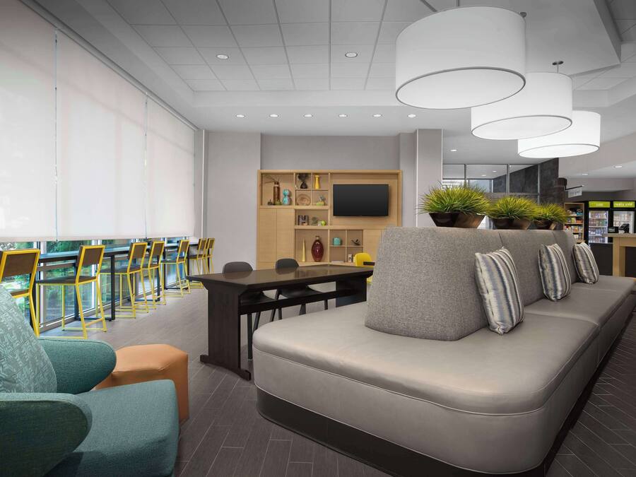 A modern lounge area with a sofa, chairs, a TV, and a bar area.