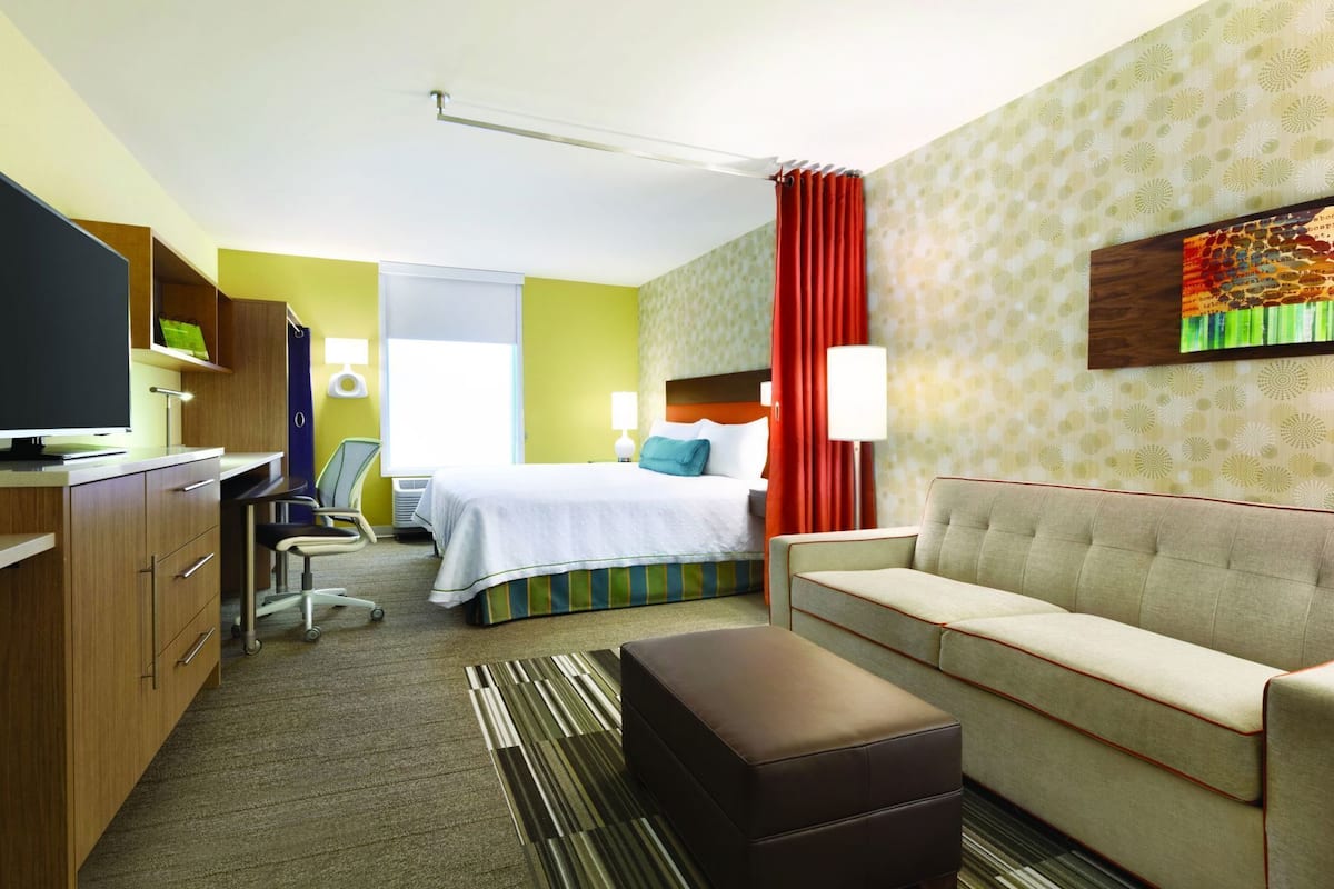 Une chambre d’hôtel comprenant un lit, un canapé, un bureau avec un ordinateur, une chaise et un téléviseur.