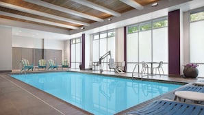 Une piscine intérieure dotée de chaises longues et d’un espace vestiaire.