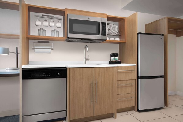 Una cocina moderna con lavavajillas, microondas, refrigerador y armarios de madera.