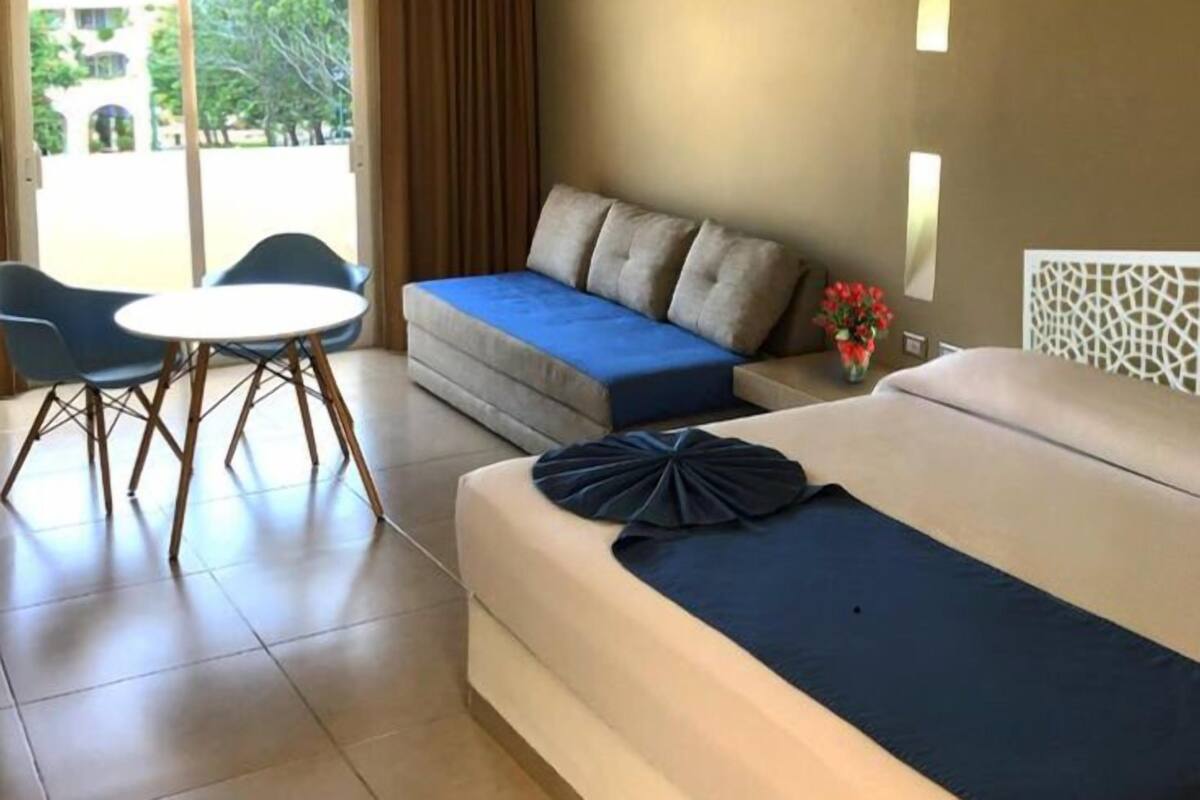 Une chambre d’hôtel avec un lit, un canapé, une table et des chaises.