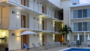 Un hôtel à plusieurs étages doté d’une piscine, de chaises longues et de parasols.