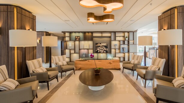 A modern lobby with a central round table, sofas arranged around it, and a wooden reception desk. - Prodigy Gramado by Wish (Gramado)
