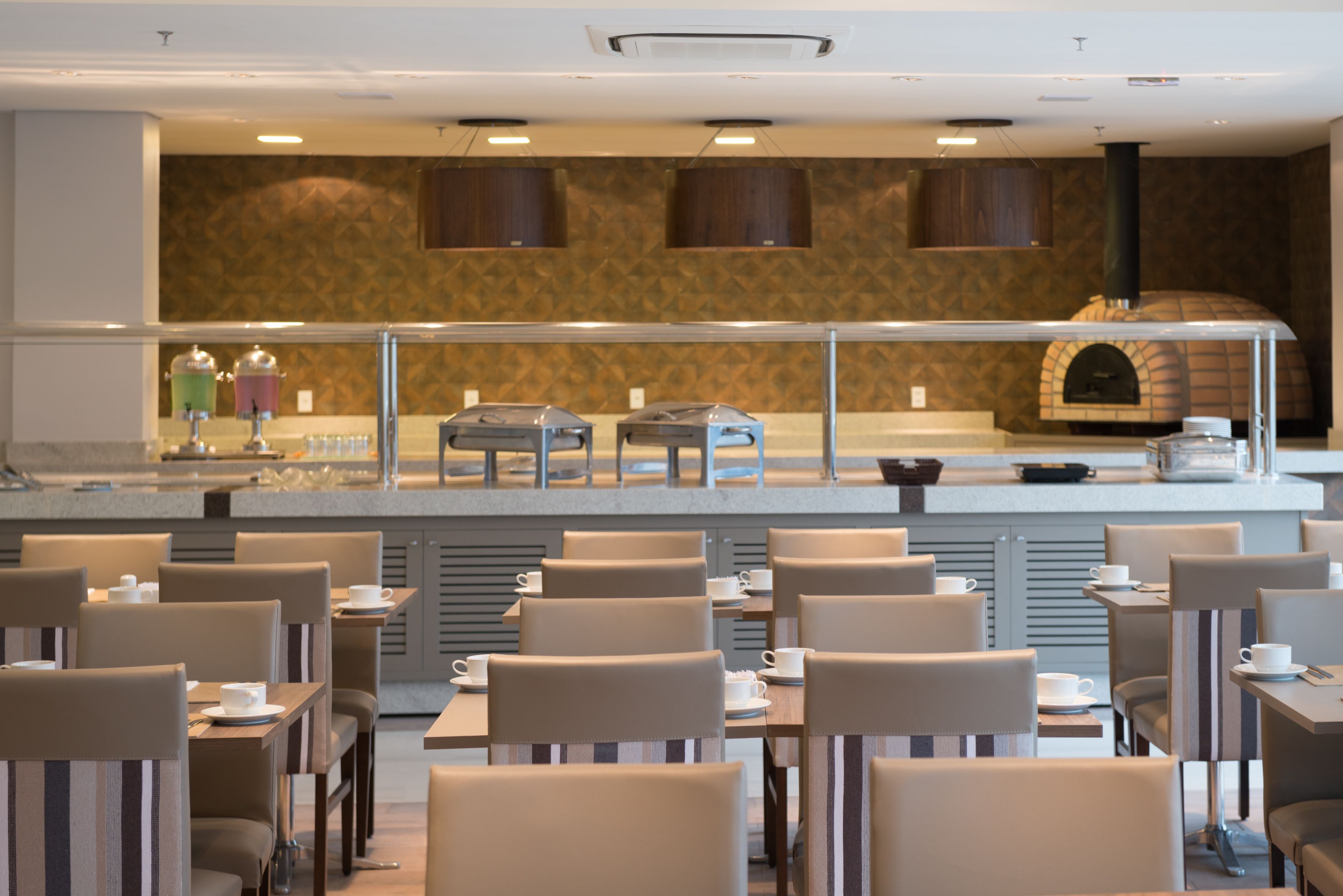 A restaurant with a counter, seating area, and a pizza oven.