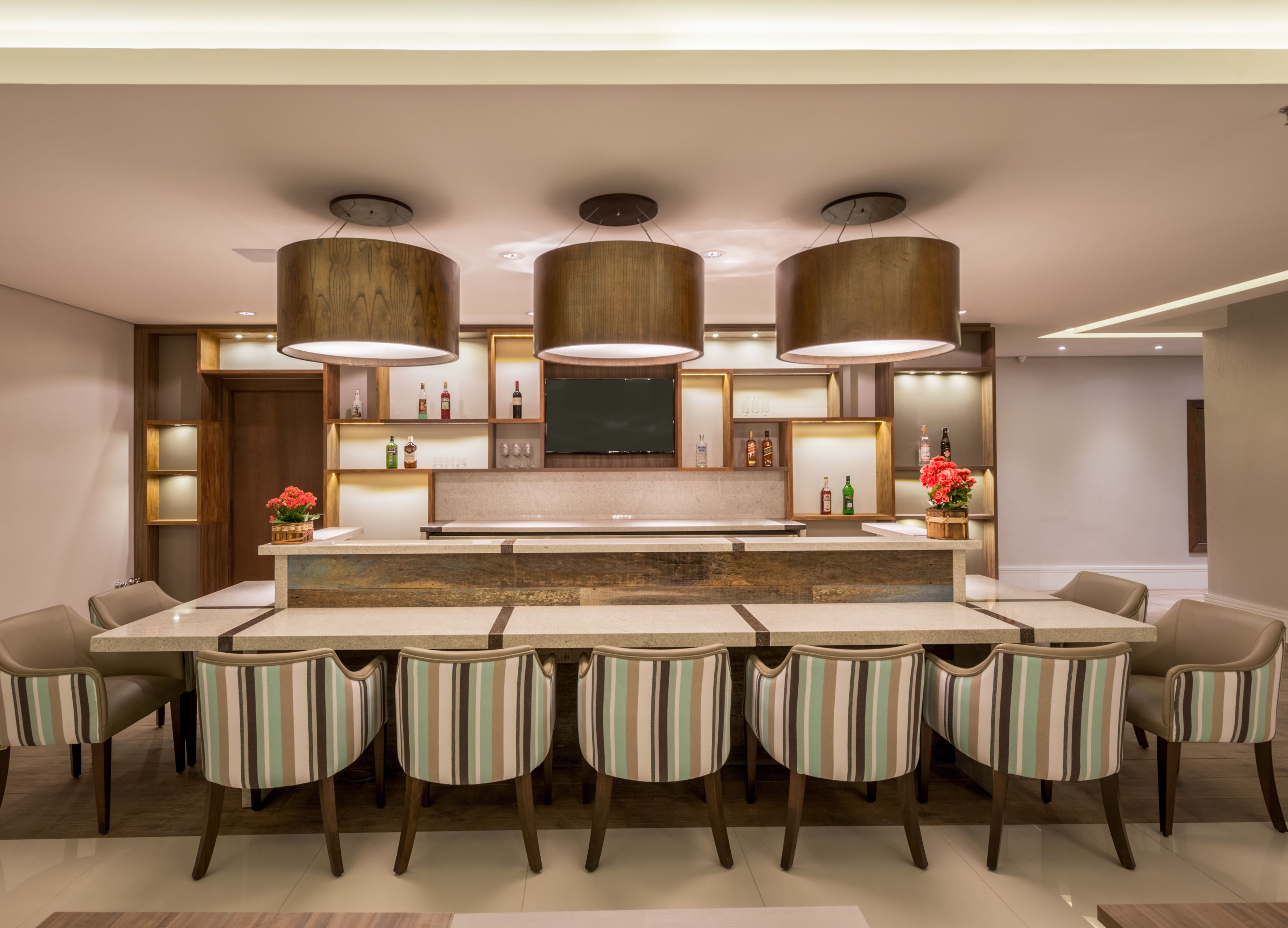 Une cuisine moderne avec un îlot central, des chaises à rayures et des luminaires suspendus.