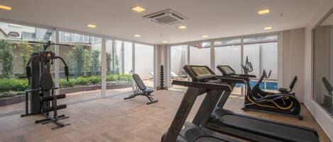 A modern gym with treadmills, a weight machine, and a bench.