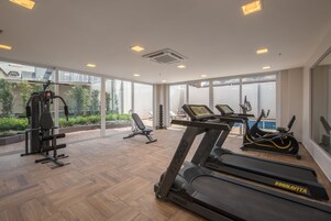 Un gimnasio moderno con cintas de correr, una máquina de pesas y un banco.