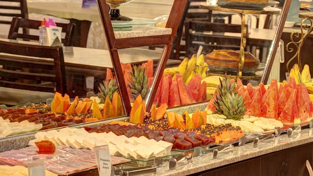 Un buffet proposant une variété de plats, notamment des fruits, des fromages et des viandes.