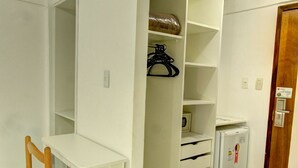 Une pièce comprenant un bureau blanc, une chaise, une armoire blanche et un petit réfrigérateur.
