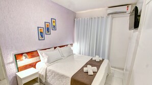 Une chambre d’hôtel avec un lit, une table de chevet, un climatiseur fixé au mur et une fenêtre avec des rideaux.