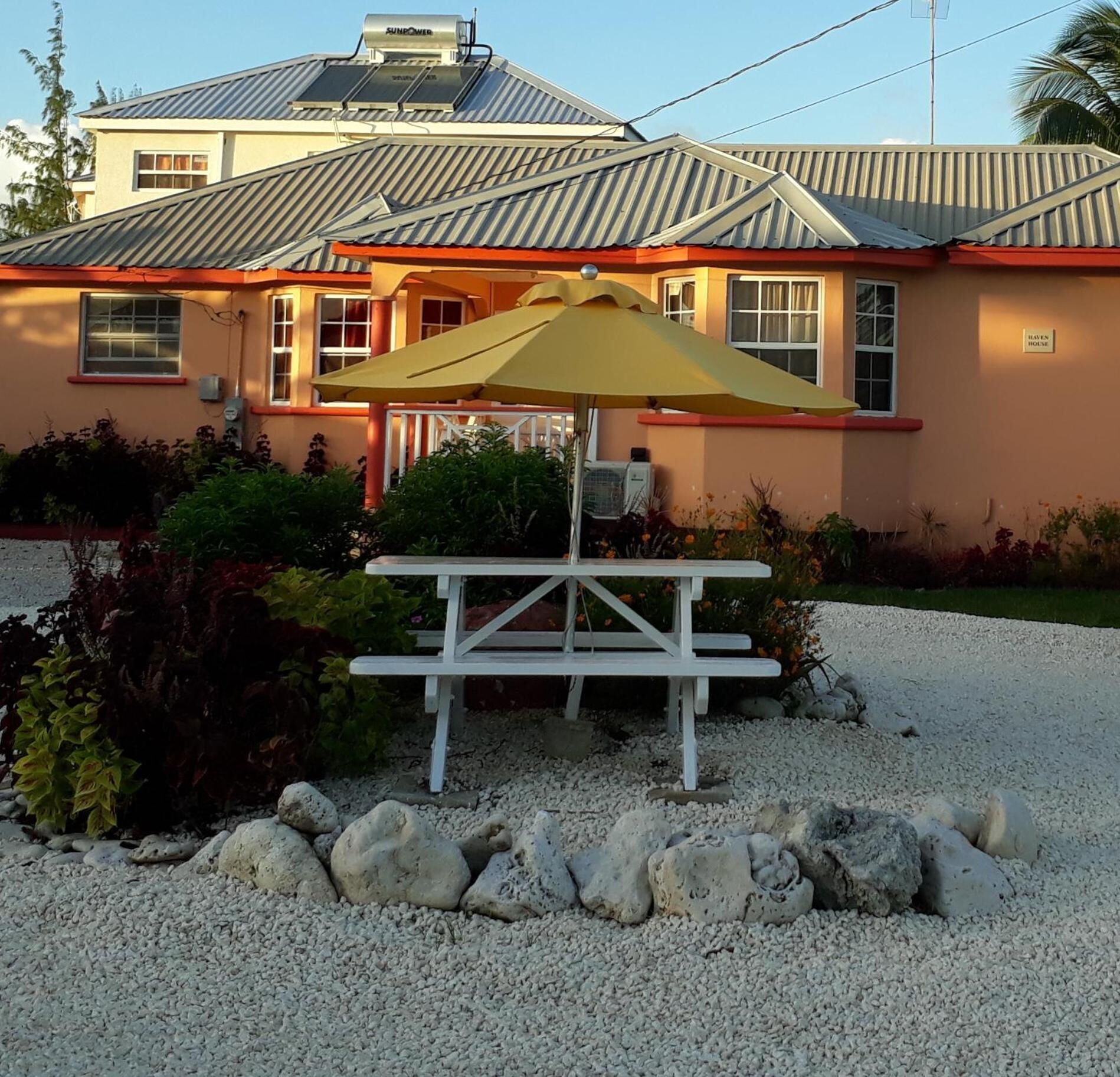 A house with a patio table and umbrella, surrounded by gravel and rocks.