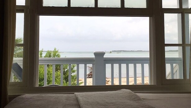 Une chambre avec vue sur la plage, grâce à une grande fenêtre.