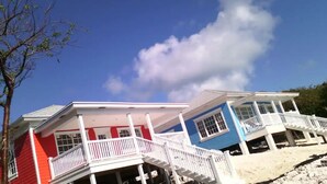 Une propriété située en bord de mer, avec des bâtiments à deux étages, des balcons blancs et un ciel d’un bleu limpide.