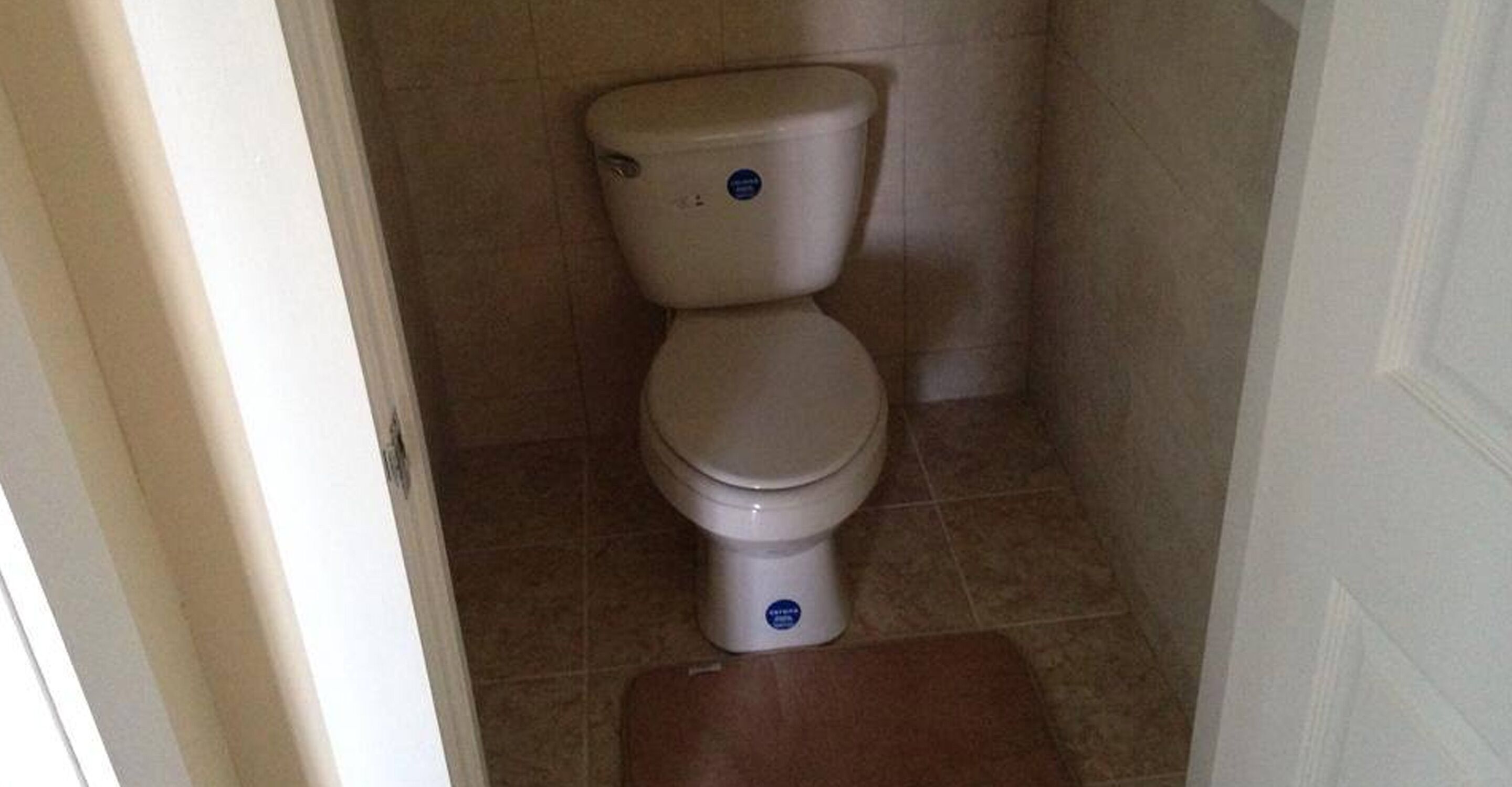 A standard toilet in a bathroom with beige tiles.