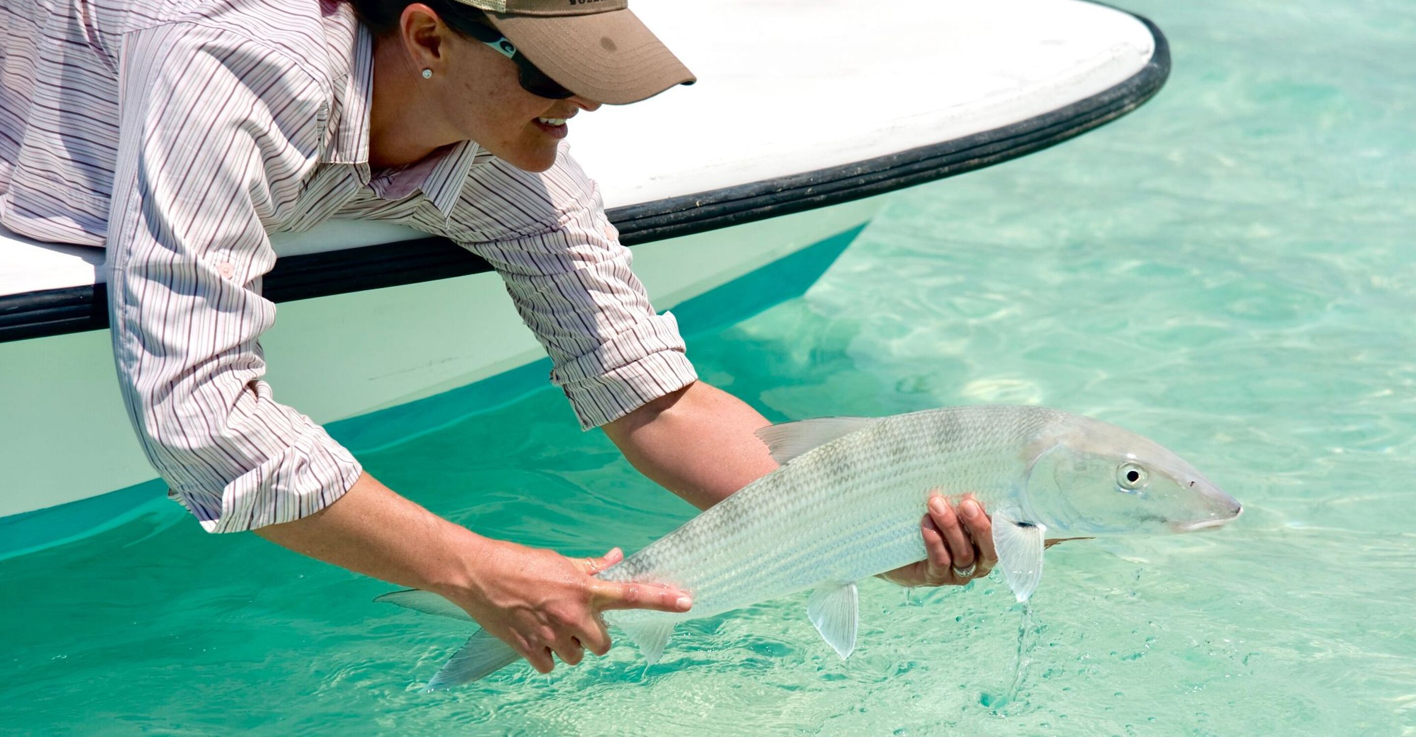 Una persona sosteniendo un pez en agua cristalina.