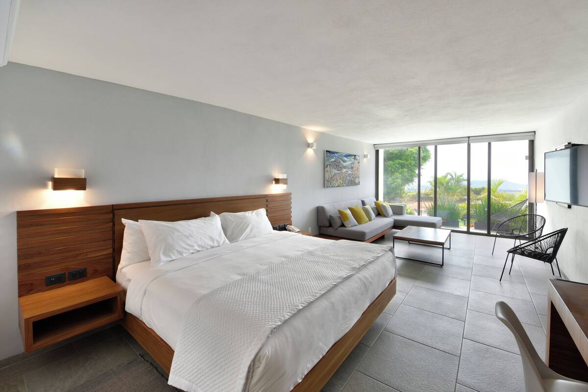 A modern bedroom with a large bed, a sofa, and a TV.