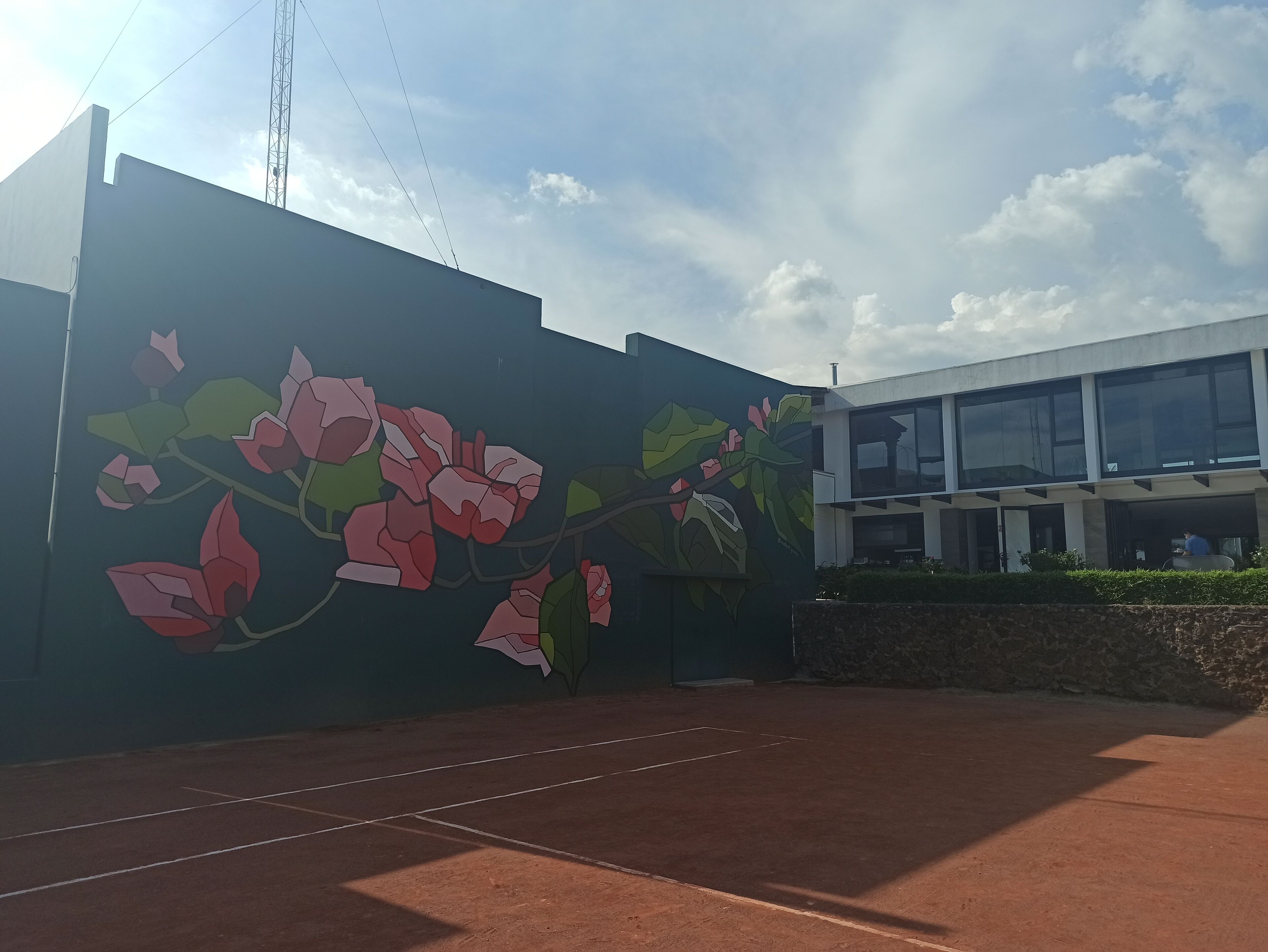 Un edificio con un mural de flores rosadas en la fachada.