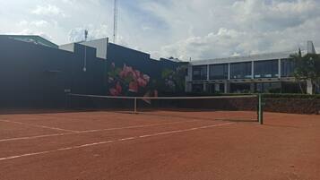 Una cancha de tenis con una red, rodeada por un edificio con un mural de flores.