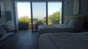 Una camera d'albergo con due letti, una sedia e vista sull'esterno.