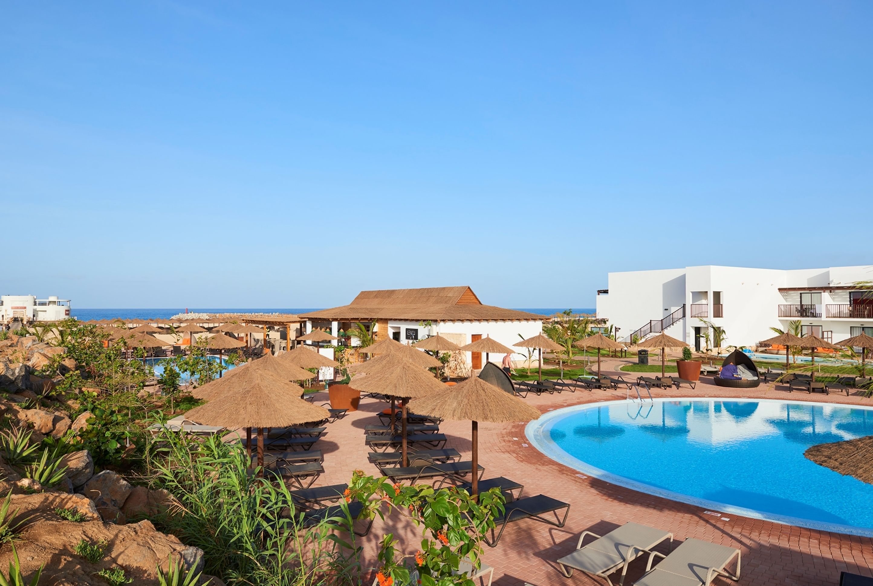 A resort with a large pool, lounge chairs, and umbrellas.