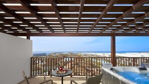 Ein Balkon mit Blick auf den Strand, einem Whirlpool und einem Tisch mit Getränken und Snacks.