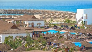 Ein Resort mit Poolbereich, Strandsonnenschirmen und Blick auf den Ozean.